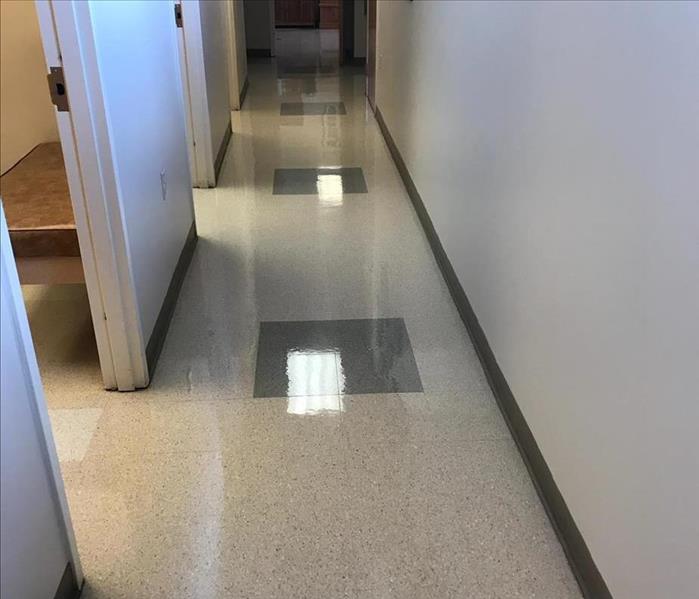 narrow hallways with sparkly tile floor and green square in the center of the floor 